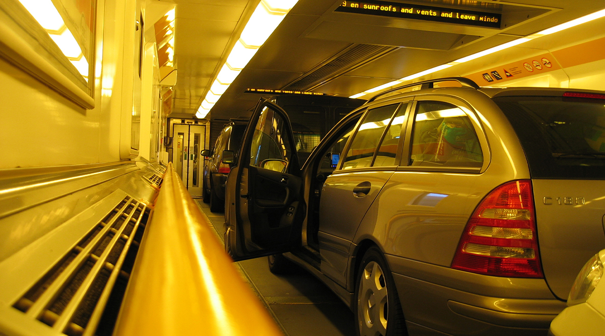 The side view of a silver car with it’s door open inside a shuttle